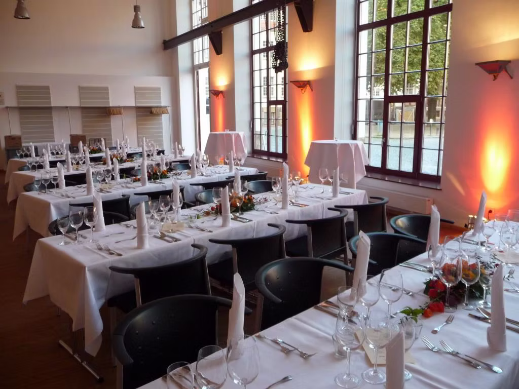 Der Saal Riemerschmid, die exklusive Eventlocation von Schmidt’s Catering Dresden, ist festlich für hochwertige Veranstaltungen vorbereitet. Die weiß eingedeckten Tische und stilvolle Beleuchtung bieten den passenden Rahmen für Premium Catering, Hochzeit Catering, Business Catering und regionales Event Catering in Dresden.
